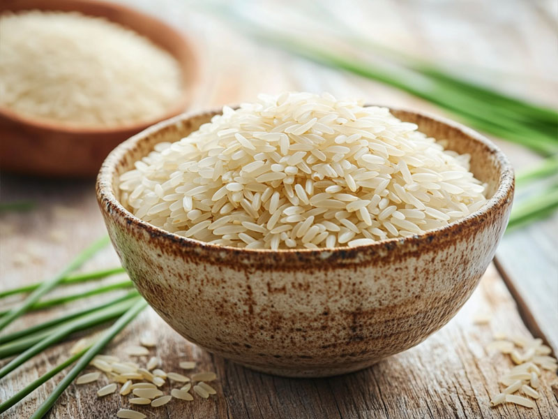 Bowl of aged basmati rice with paddy stalks