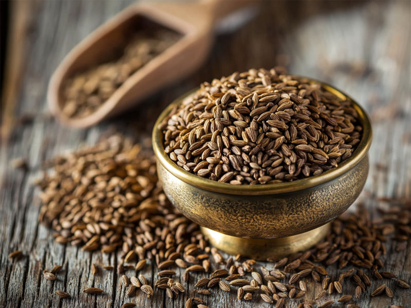 Organic whole cumin seeds in a brass bowl