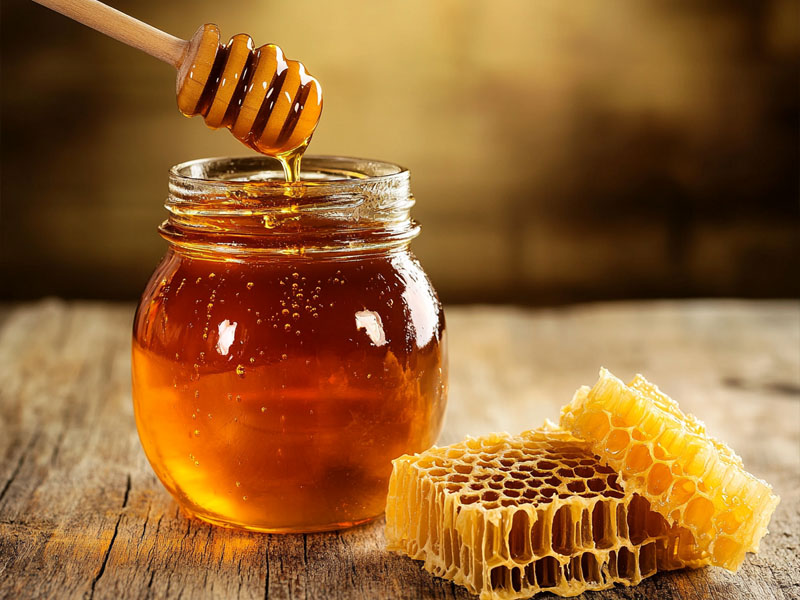 Raw organic honey with wooden dipper and honeycomb