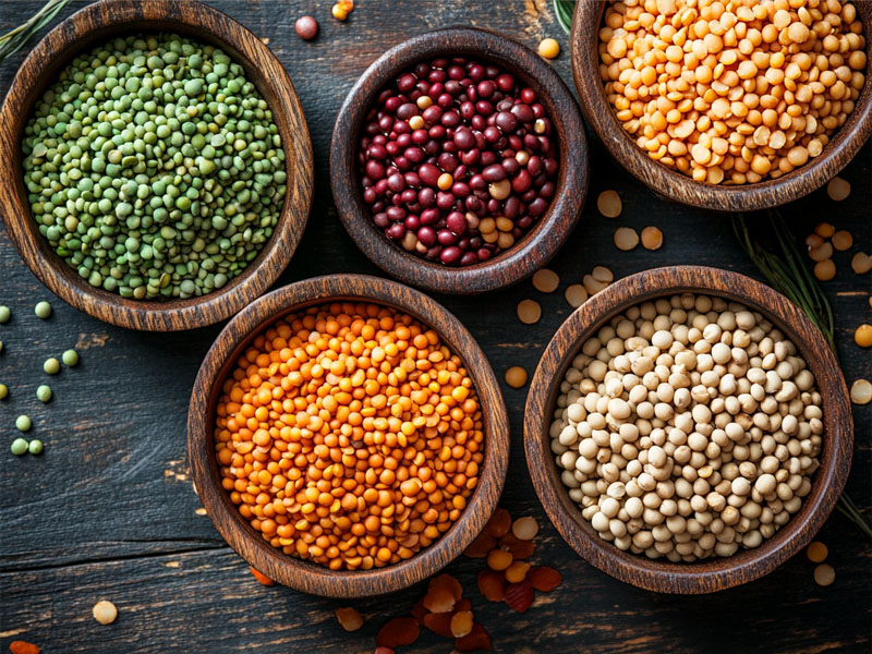 Variety of organic whole pulses in wooden bowls